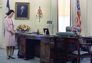 U.S. First Lady Claudia "Lady Bird" Johnson looking on as U.S. President Lyndon Johnson telephones