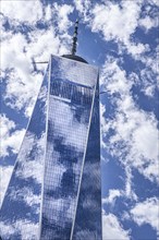 One World Trade Center, low angle view, building exterior against clouds and blue sky, New York