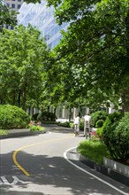 Rear view of couple, one with small child, riding bicycles on bicycle path with 200 West Street in