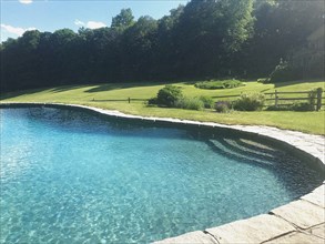 Swimming pool surrounded by scenic landscape and gardens