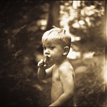 Young boy in woods making silence gesture with finger pressed to lips