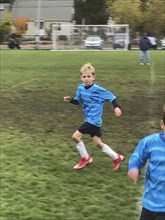 Young boy in soccer uniform running on soccer field