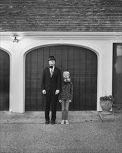 Full-length portrait of mid-adult businessman and teen boy wearing gas masks in front of garage