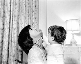 U.S. First Lady Jacqueline Kennedy laughing as her son, John F. Kennedy, Jr., plays with her