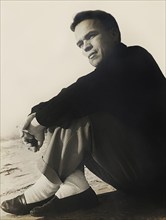 Contemplative mid-adult man sitting on sandy beach