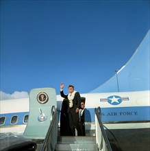 U.S. President John F. Kennedy (wearing flower leis) waving to crowd from stairs of Air Force One