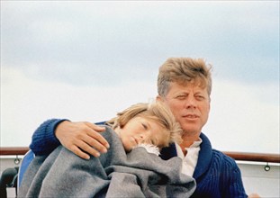 U.S. President John F. Kennedy sitting with his arm around his daughter, Caroline Kennedy, aboard