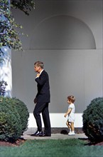 U.S. President John F. Kennedy walking with his son, John F. Kennedy, Jr., along West Wing