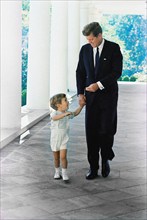 U.S. President John F. Kennedy walking with his son, John F. Kennedy, Jr., along West Wing