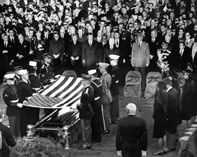 Members of the Kennedy family, officials, and dignitaries look on as honor guard pallbearers lift