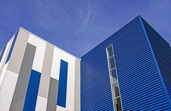 Low angle view of geometric building exterior, against blue sky