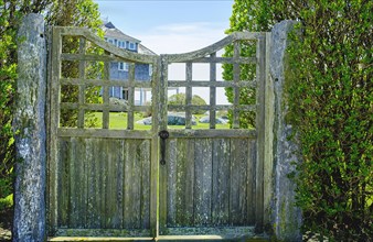 Weathered wood gate with large home in background