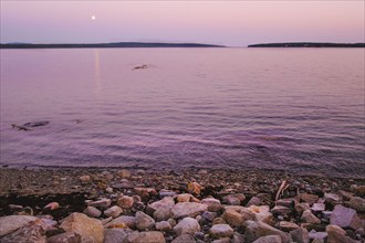 Moonrise at dusk over harbor