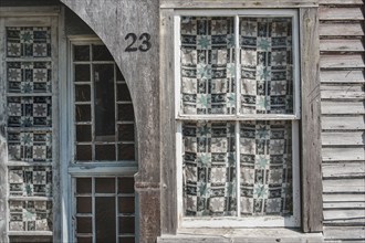 Weathered building exterior with pane windows covered in patterned curtains