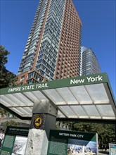 Low angle view of residential skyscraper and information kiosk for Empire State Trail, Battery Park