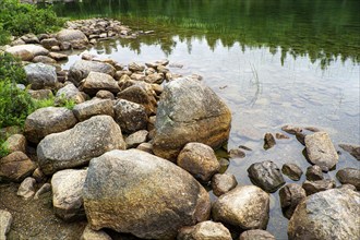 Large rocks at edge of clear lake, Acadia National Park, Maine, USA