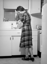 Mother preparing baby's bottle, Kearny Mesa defense housing project, San Diego, California, USA,