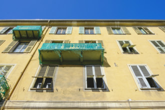 Low angle view of apartment building with shutters on windows and two balconies