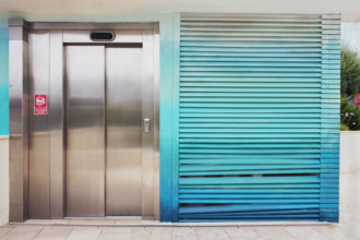 Metal elevator door next to wall with turquoise slats