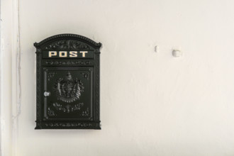 Black metal mailbox on white wall