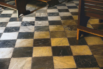 Old wood church pews on marble floor with black and white checkered pattern