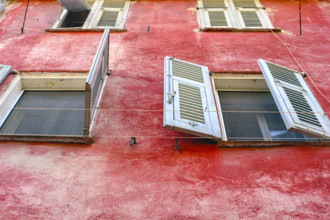 Low angle view of shuttered windows and empty clothes lines against red building exterior