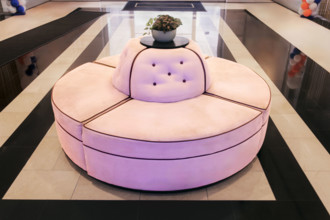 Pink circular couch on marble floor in hotel lobby