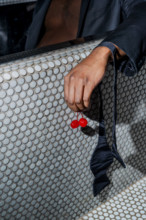 Two cherries dangling from man's hand while he is sitting in a bathtub