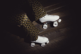 Woman wearing white roller skates and flaired pants with a geometric pattern