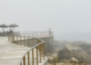 Group of people enjoying outdoor restaurant overlooking sea on misty morning