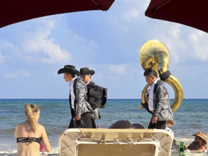 Three musicians walking along tourist beach, Playa del Carmen, Mexico