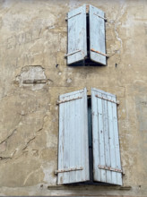 Blue weathered wood shutters on cracking building façade, Dordogne, France