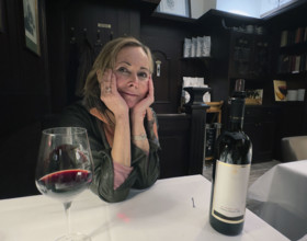 Mid-adult woman sitting at table having a glass of wine