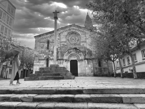 Woman with umbrella walking towards old church, A Caruña, Galicia, Spain