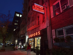 Liquor store and street scene at night, Chelsea, New York City, New York, USA