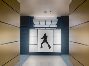 Men's public bathroom entrance with silhouette of Elvis Presley on wall