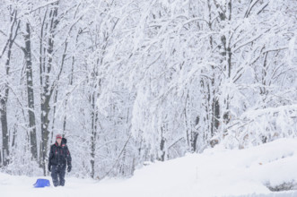 Teen boy pulling plastic sled in snowy landscape