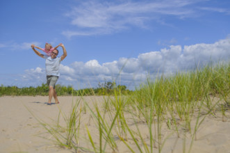 Father carrying daughter on shoulders at beach