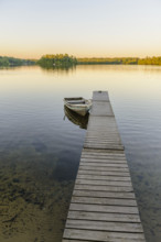 Row boat moored at dock on scenic lake at sunset