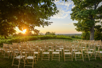 Rows of wood folding chairs set up for outdoor event at sunset