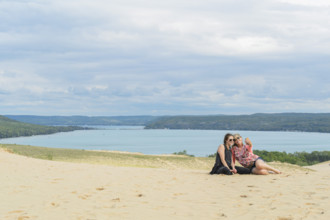 Mother and daughter taking a selfie atop sand dunes at beach