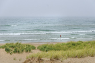 Rear view of swimmer wading into lake on cloudy day