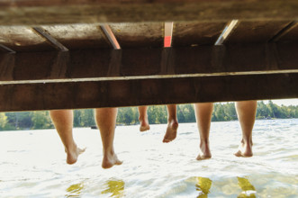 Family with dangling feet sitting on dock