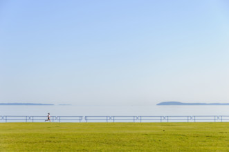 Young adult woman running along lake