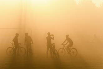 Silhouette of four cyclists waiting in fog for start of bike race