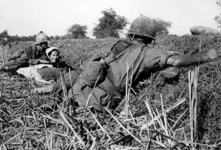 American soldier of 1st Infantry Division motioning to woman refugee to keep her children's heads