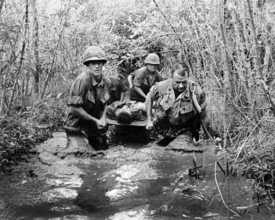 U.S. soldiers carrying wounded comrade through swampy area, Vietnam, U.S. Army Signal Corps, 1969