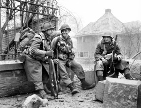 American Infantrymen pause to rest en route to front lines, Left to right, Sgt. Lyle Greene,