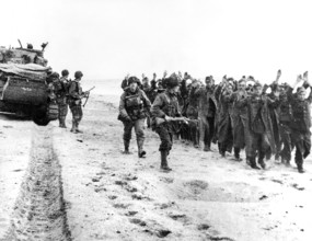 American soldiers marching group of German prisoners along beachhead after which they will be sent