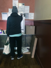 Rear view of man checking mailbox in apartment building lobby, Brooklyn, New York, USA